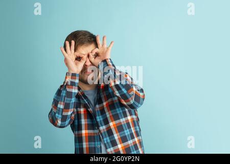 Funny young Caucasian bearded man in casual clothes isolated on light blue background. Having fun. Stock Photo