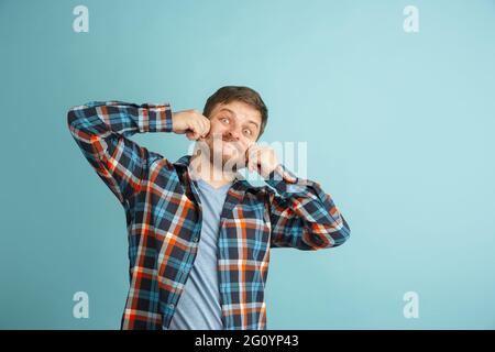 Funny young Caucasian bearded man in casual clothes isolated on light blue background. Having fun. Stock Photo