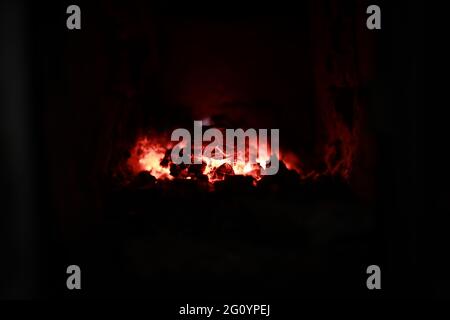 heated stove in the house with red coals and fire Stock Photo