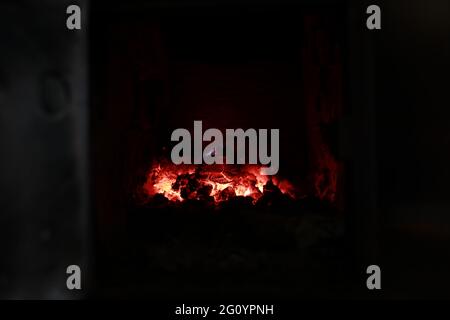 heated stove in the house with red coals and fire Stock Photo