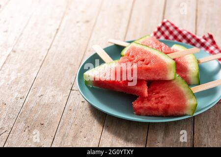 Watermelon slices popsicles on blue plate on rustic wooden table Stock Photo
