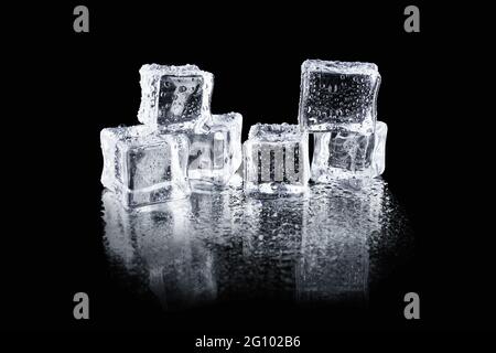 Transparent wet ice cubes with water droplets on a black reflective surface Stock Photo