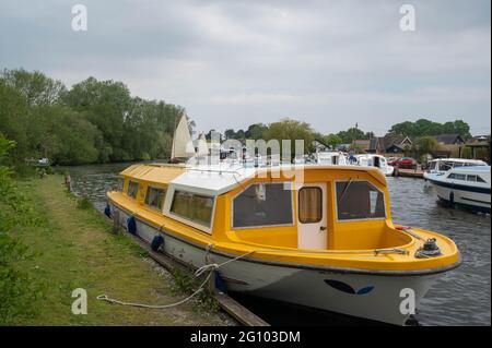 Norfolk Broads river bank with a motor cruiser tied up on a busy part of the River Bure Stock Photo