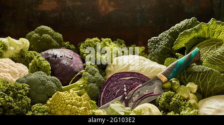 Pile of assorted types of cabbages placed on counter with knife at local grocery market Stock Photo