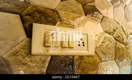 Dirty electricity on off switch with colorful tiles background. Old white light switch. Stock Photo
