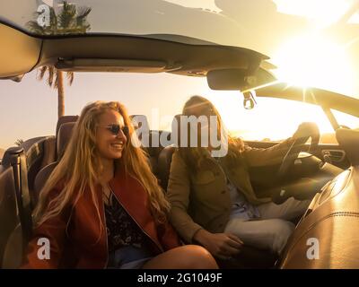 Romantic couple enjoying holidays driving a convertible car on the road at sunset. People rent car at vacations. Transport , people and lifestyle. Stock Photo