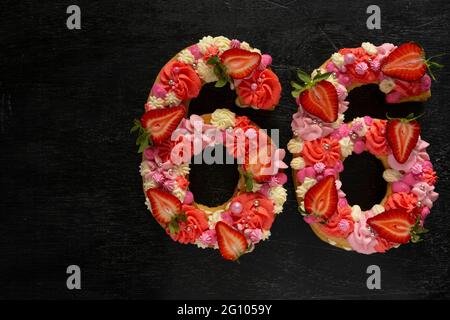 Beautiful cake in the shape of number 66. Modern trendy design. Springtime decoration. Copy space. Low key. Unusual bright dessert. Birthday card. Stock Photo
