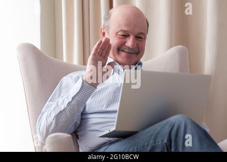 Man sitting in the living room and having videochat on the laptop computer Stock Photo