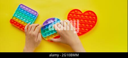 Kid hands playing with colorful pop It fidget toy. Colorful antistress sensory toy fidget push pop it. Stock Photo