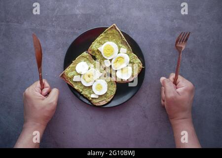 young man hand waiting for eating avocado, brown bread Stock Photo