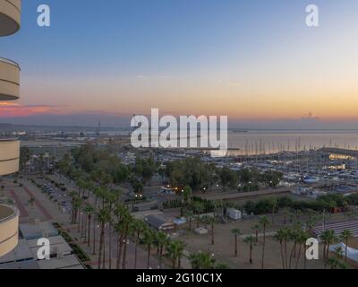 Top aerial view overlooking the sunrise at Finikoudes Palm tree promenade and pier with yachts near the Mediterranean sea in Larnaca city, Cyprus. Stock Photo