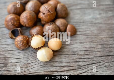 Organic Macadamia nuts with shell on wooden table Stock Photo