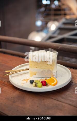 Coconut vanilla cake with whipped cream and berry fruits on plate in bakery shop Stock Photo