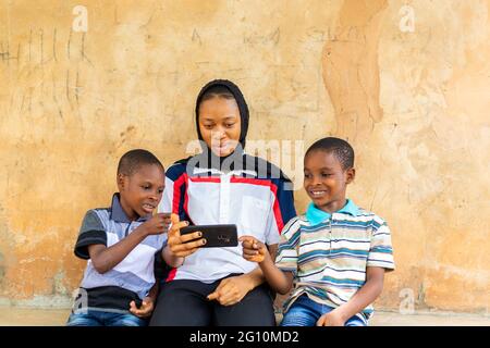 young pretty african lady and her brothers did thumbs up to what they saw on the phone Stock Photo