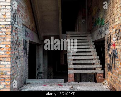 The staircase inside an unfinished suspended construction of an old time-worn dirty brick building with graffiti on the walls in the center of Kyiv. Stock Photo