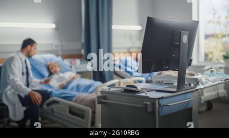 Hospital Ward: Modern Advanced High-Tech Medical Computer. In the Background Modern Equipment Clinic Surgeon Using Tablet Computer Consulting Patient Stock Photo