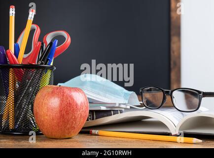 Classroom desk with school supplies and blank blackboard in background for copy space Stock Photo