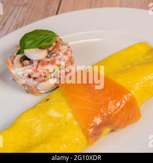 Omelette with salmon and tomatoes, served on plate, traditional Norwegian dish Stock Photo