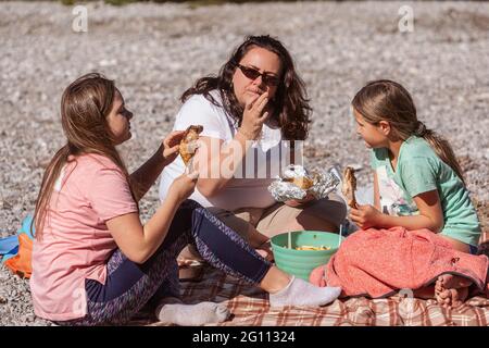 Single mother with her two little daughters, eating at a rest stop during a hike Stock Photo