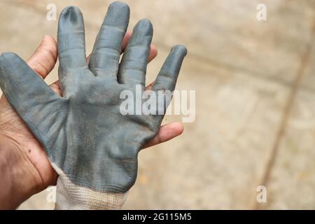 Working gloves held in hand after garden works with clean hands underneath. Protective gloves to safeguard hands on work process Stock Photo