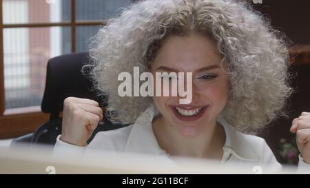 Pretty young curly white-haired girl getting university admission notification or employment offer email, feeling excited of reading good news. Close- Stock Photo