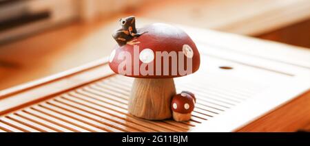 A small frog sitting on a fly agaric. Clay tea figurine, teapet.  Stock Photo