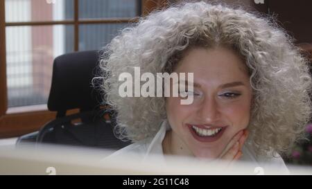 Happy curly white-haired woman talking at an online conference at home. Stock Photo