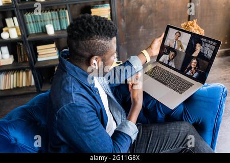 Successful male black freelancer talking on conference video call to colleagues online. Afro American student talking to teacher and other students on Stock Photo