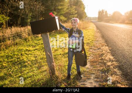 Canada, Ontario, Boy standing at mailbox on roadside at sunset Stock Photo