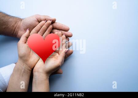 Romantic Couple Relationship And Health Insurance. Hand Holding Heart Stock Photo