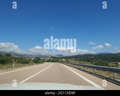 View of an empty mountainous road with right turn road sign taken from inside moving car. Stock Photo