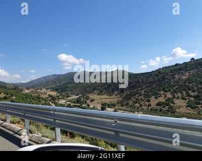 View of an empty mountainous road with right turn road sign taken from inside moving car. Stock Photo