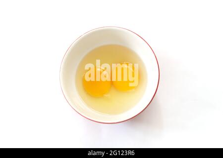 Raw eggs, top view of two raw eggs yolk in bowl on isolated white background. Stock Photo