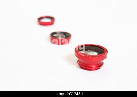 Smartphone lenses, various phone lenses lined up on isolated white background, mobile photography tools. Stock Photo