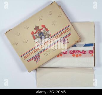 National breakfast sheet. National breakfast sheet (a) in original packaging (b). In the box a letter from the supplier with a description of this breakfast sheet. White Damask tablecloth with the edge red-white-blue-orange. Orange apple motif and white woven decoration. In the middle the Dutch lion with shield, which straighten through the swastika with a dagger. In front of a church tower with underneath inscription. Name of late and laundry number. Lid of the box in red, white, blue and gold printed. Eight peace pigeons with ribbon in beak. In the middle crown with cloak in which two lions Stock Photo