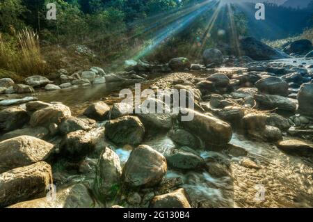 River water flowing through rocks at dawn, sun light beams on the water, beautiful Reshi River, Sikkim, India - stock image of rivers in India