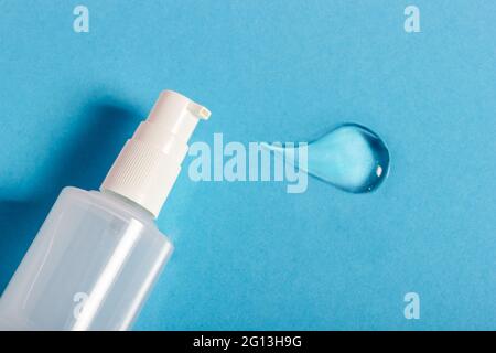 Hydrating sanitizer blob gel in glass pump bottle. Transparent serum or moisturizer texture for skin treatment and hygiene on blue Stock Photo