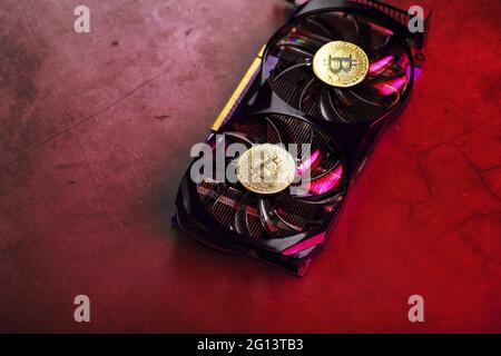 On the fans of a powerful video card, the coins of the Bitcoin cryptocurrency with a red backlight are displayed.The concept of mining and mining of c Stock Photo