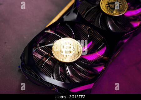 On the fans of a powerful video card, the coins of the Bitcoin cryptocurrency with a red backlight are displayed.The concept of mining and mining of c Stock Photo