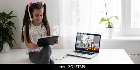 Little girl studying online using her laptop at home Stock Photo