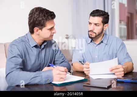 Two serious males with documents at table Stock Photo