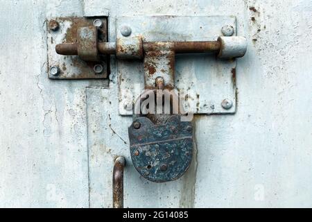 Close up view of old weathered lock on the metal door - old abandoned garage doors with padlock. Selective focus Stock Photo
