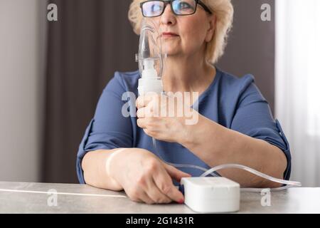 Elderly woman using asthma machine at home Stock Photo