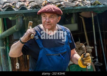 portrait of mature blacksmith. Iron worker in workshop outdoors in the countryside Stock Photo