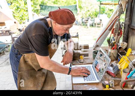 portrait of mature blacksmith. Worker on the computer in the laboratory in the countryside Stock Photo