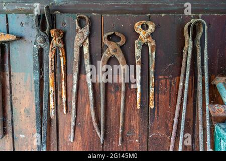 rusty blacksmith tools hanging on a wooden board Stock Photo