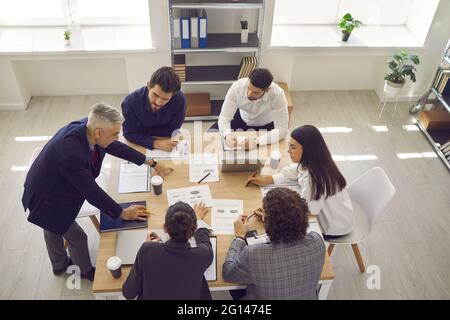 Business team analyzes sales charts and diagrams, develops a new strategy and discusses work issues. Stock Photo
