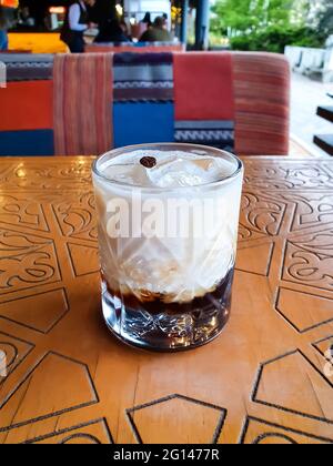 White Russian cocktail, alcoholic mixed drink, alcohol beverage on the wooden table in restaurant, cocktail with ice and coffee bean in a glass in a s Stock Photo