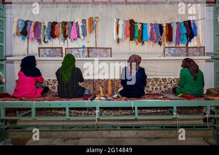 Iranian women weaving Persian rugs in the carpet workshop in Naein, Iran. Stock Photo