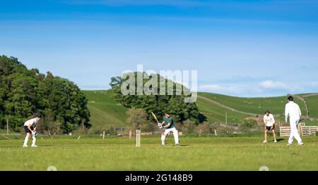 Wensleydale, UK. 04th June, 2021. 4 June 2021 - Hawes, North Yorkshire - Village cricket in what has to be one of the most scenic little grounds as Hawes bat on their home ground at Haylands on the banks of the River Ure. Credit: Wayne HUTCHINSON/Alamy Live News Stock Photo